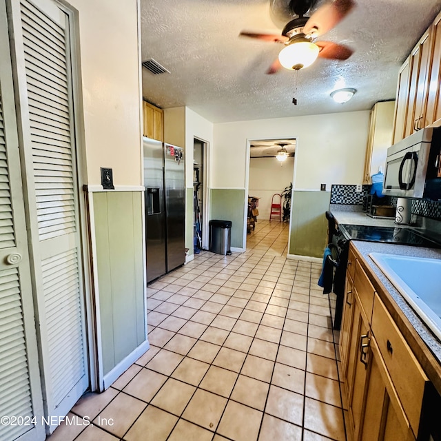 kitchen featuring light tile patterned floors, a textured ceiling, and appliances with stainless steel finishes