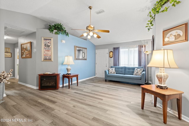 living room featuring ceiling fan, light wood-type flooring, a textured ceiling, and vaulted ceiling