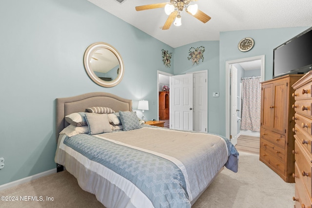 carpeted bedroom featuring ensuite bath, ceiling fan, and lofted ceiling