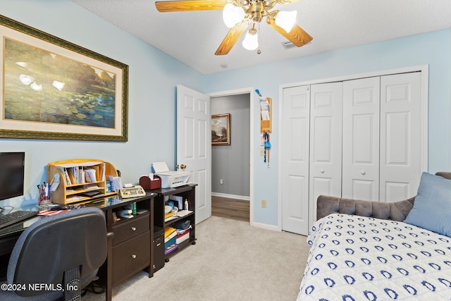 bedroom featuring a textured ceiling, ceiling fan, light carpet, and a closet