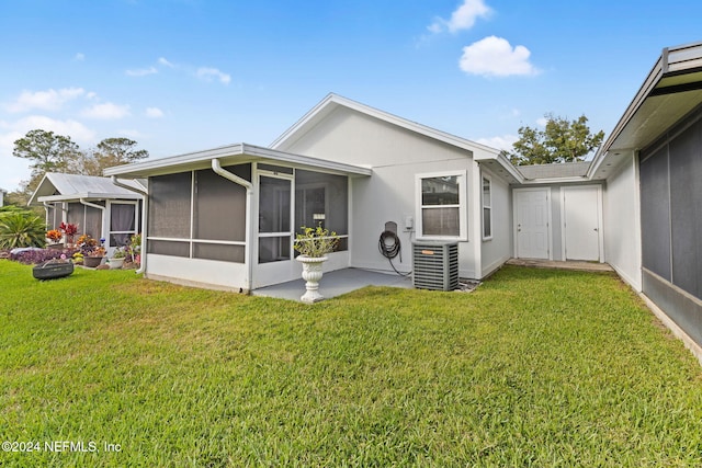 rear view of property featuring a sunroom, central air condition unit, and a lawn