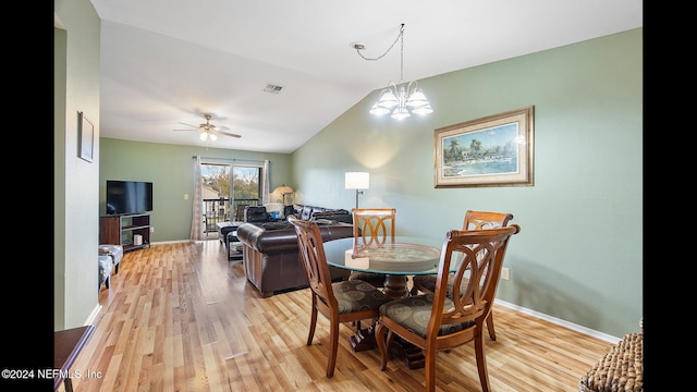 dining space featuring ceiling fan with notable chandelier, light wood-type flooring, and vaulted ceiling