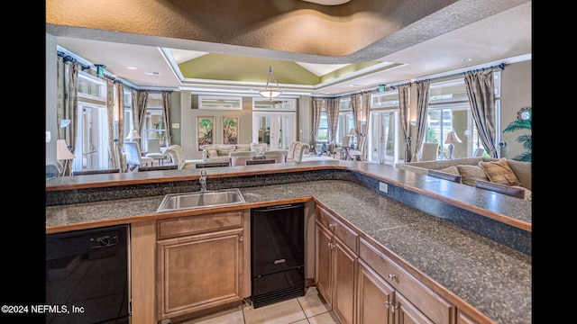 kitchen featuring dishwasher, french doors, sink, a raised ceiling, and light tile patterned flooring