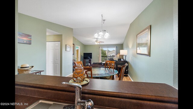 dining room with ceiling fan with notable chandelier and vaulted ceiling