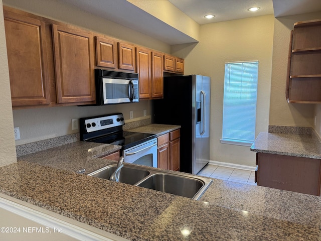 kitchen featuring stone counters, sink, light tile patterned floors, kitchen peninsula, and stainless steel appliances