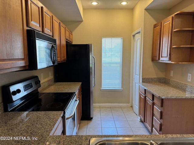 kitchen with electric range, light tile patterned flooring, and light stone countertops