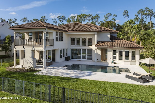 rear view of house featuring a lawn, outdoor lounge area, a balcony, a fenced in pool, and a patio