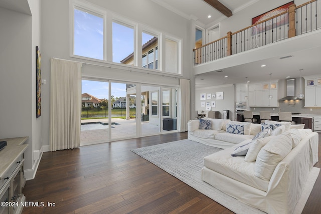 living room with beam ceiling, dark hardwood / wood-style flooring, a towering ceiling, and a healthy amount of sunlight