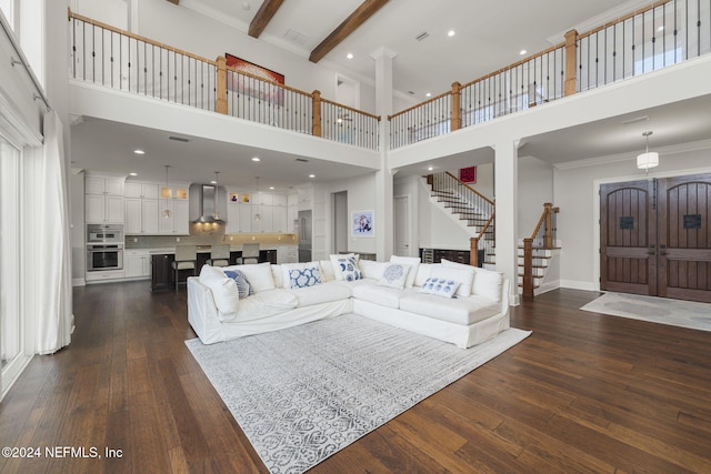 living room with beamed ceiling, dark hardwood / wood-style flooring, a towering ceiling, and ornamental molding