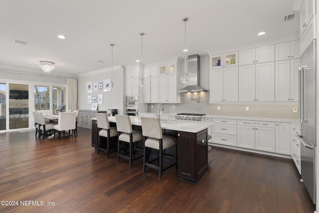 kitchen featuring white cabinets, wall chimney exhaust hood, a kitchen island with sink, and dark wood-type flooring