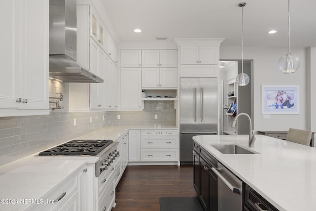 kitchen featuring light stone counters, hanging light fixtures, stainless steel appliances, and wall chimney range hood