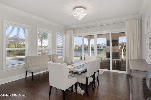 dining space with a chandelier, dark hardwood / wood-style floors, a fireplace, and crown molding