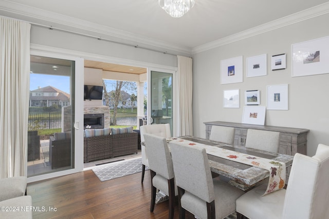 dining space featuring crown molding, a fireplace, dark hardwood / wood-style floors, and an inviting chandelier