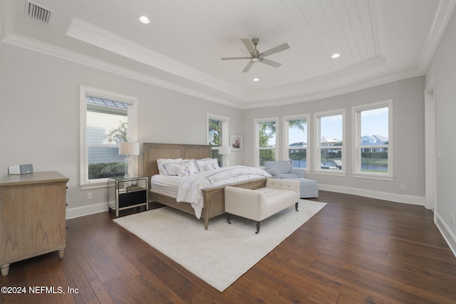 bedroom featuring a tray ceiling, multiple windows, ceiling fan, and dark hardwood / wood-style flooring