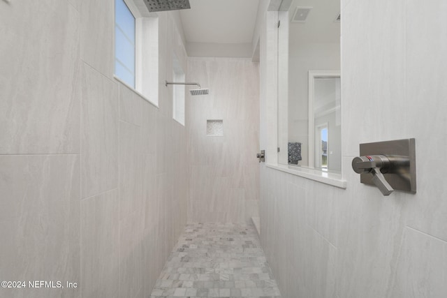 bathroom with a tile shower and plenty of natural light