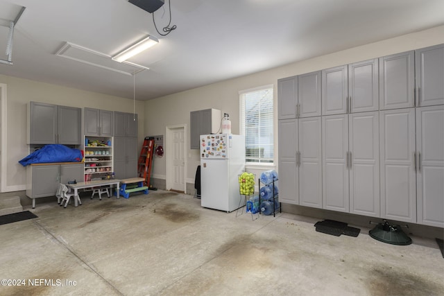 garage featuring white fridge and a garage door opener