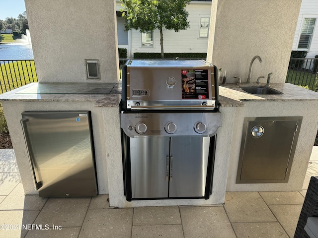 view of patio with grilling area, sink, and a water view