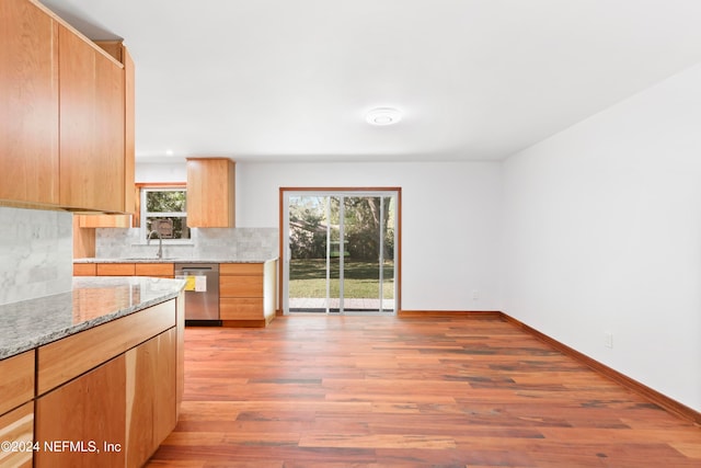 kitchen featuring dishwasher, sink, light stone counters, light hardwood / wood-style flooring, and decorative backsplash