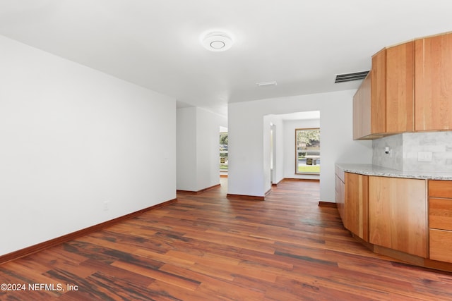 kitchen with backsplash, light stone countertops, and dark hardwood / wood-style flooring