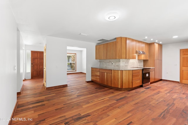 kitchen featuring decorative backsplash, black range, dark wood-type flooring, and range hood