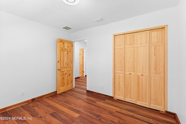 unfurnished bedroom with a closet and dark wood-type flooring