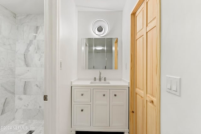 bathroom featuring tiled shower and vanity