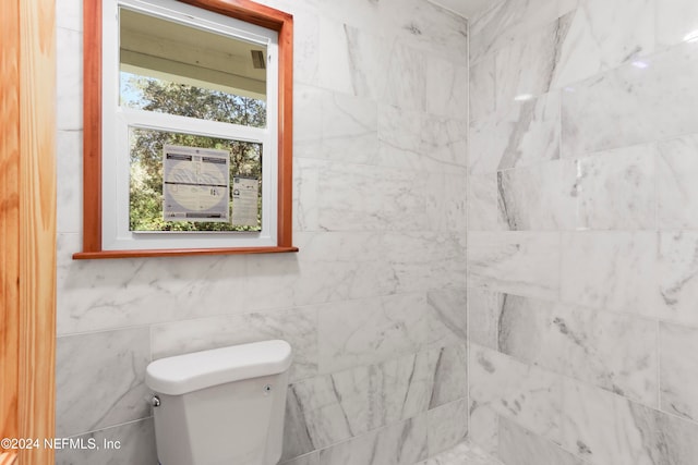 bathroom featuring toilet and tile walls