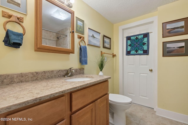 bathroom featuring tile patterned floors, vanity, toilet, and a textured ceiling