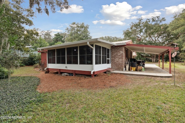 rear view of property with a sunroom, a patio area, and a yard