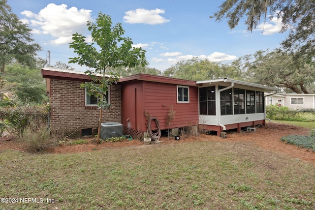 rear view of house with a lawn, a sunroom, and cooling unit