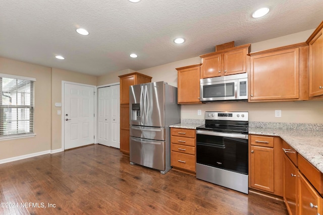 kitchen featuring dark hardwood / wood-style floors, light stone countertops, a textured ceiling, and appliances with stainless steel finishes