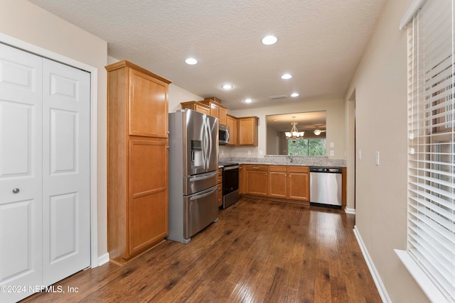 kitchen featuring a textured ceiling, stainless steel appliances, an inviting chandelier, and dark hardwood / wood-style floors