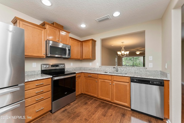 kitchen featuring appliances with stainless steel finishes, a textured ceiling, sink, a notable chandelier, and dark hardwood / wood-style floors