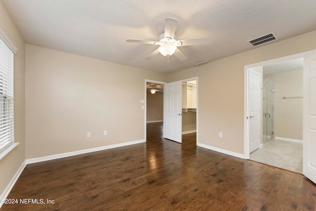 unfurnished bedroom featuring dark hardwood / wood-style flooring, ensuite bathroom, a spacious closet, and ceiling fan