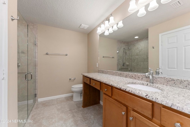 bathroom featuring a shower with door, vanity, a textured ceiling, and toilet