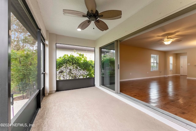 unfurnished sunroom with ceiling fan