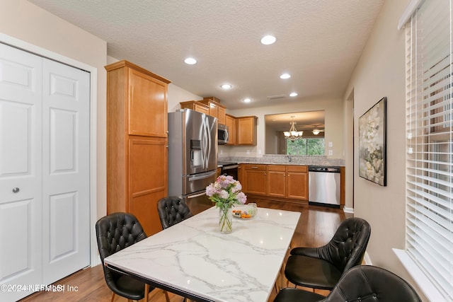 dining space featuring a chandelier, sink, a textured ceiling, and dark wood-type flooring