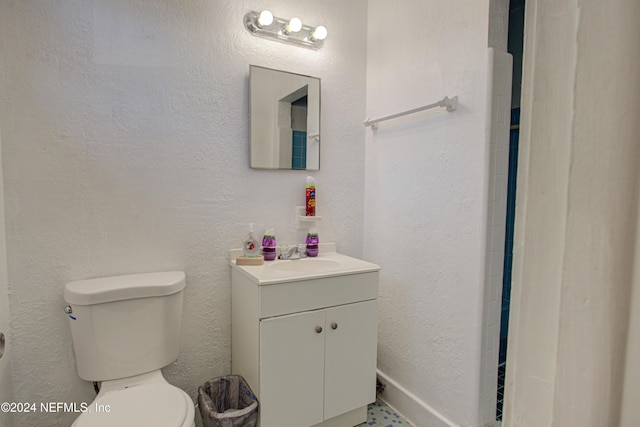 bathroom featuring a textured wall, vanity, and toilet