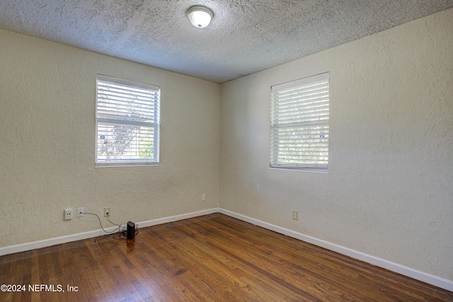 spare room with baseboards, dark wood-style flooring, and a textured wall