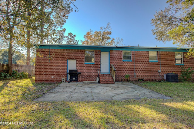 rear view of property with entry steps, brick siding, a yard, and a patio