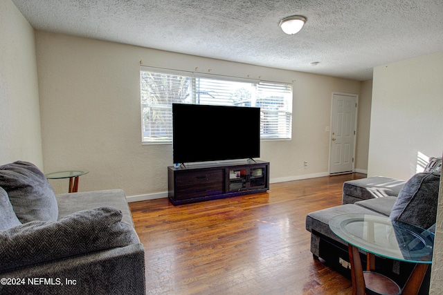 living area with baseboards, dark wood finished floors, and a textured ceiling