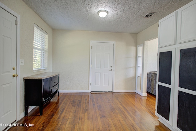 entrance foyer featuring dark wood-style floors, a textured ceiling, visible vents, and baseboards