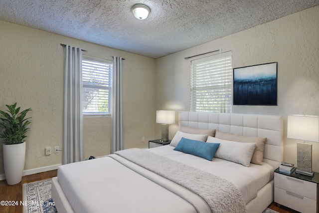 bedroom with dark wood-style floors, baseboards, a textured ceiling, and a textured wall