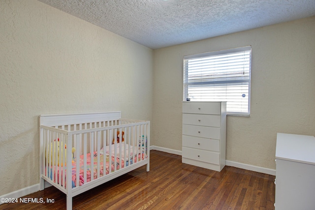 unfurnished bedroom with a textured ceiling, a textured wall, dark wood-style flooring, and baseboards