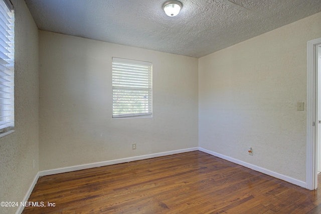 unfurnished room with dark wood-style floors, a textured ceiling, and baseboards