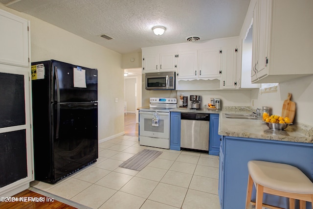 kitchen with stainless steel appliances, light countertops, a sink, and white cabinetry