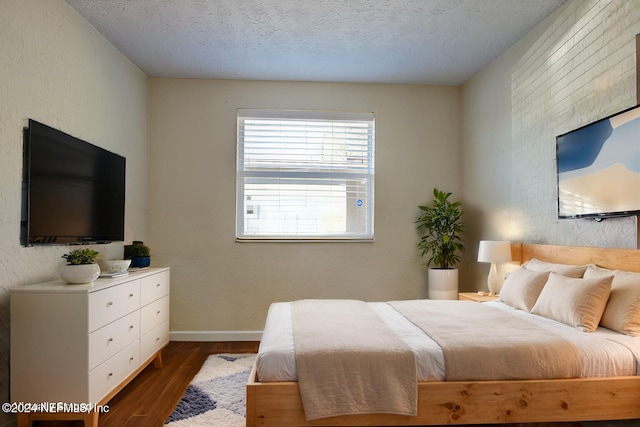 bedroom featuring a textured ceiling, dark wood-style flooring, and baseboards