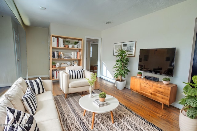 living area featuring visible vents and wood finished floors