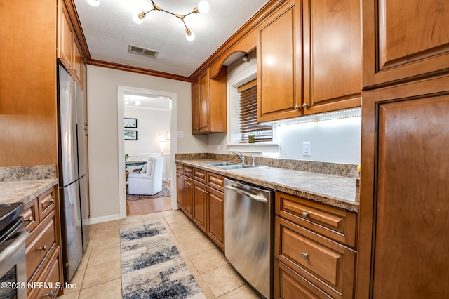 kitchen with crown molding, sink, a textured ceiling, light tile patterned flooring, and stainless steel appliances