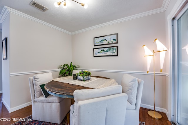 dining area featuring a textured ceiling, dark wood-type flooring, and ornamental molding